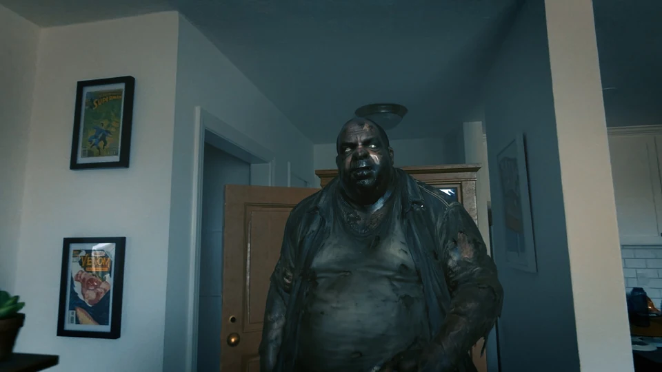 A large infected man fills the foreground in front of an open wooden doorway in a real living room.